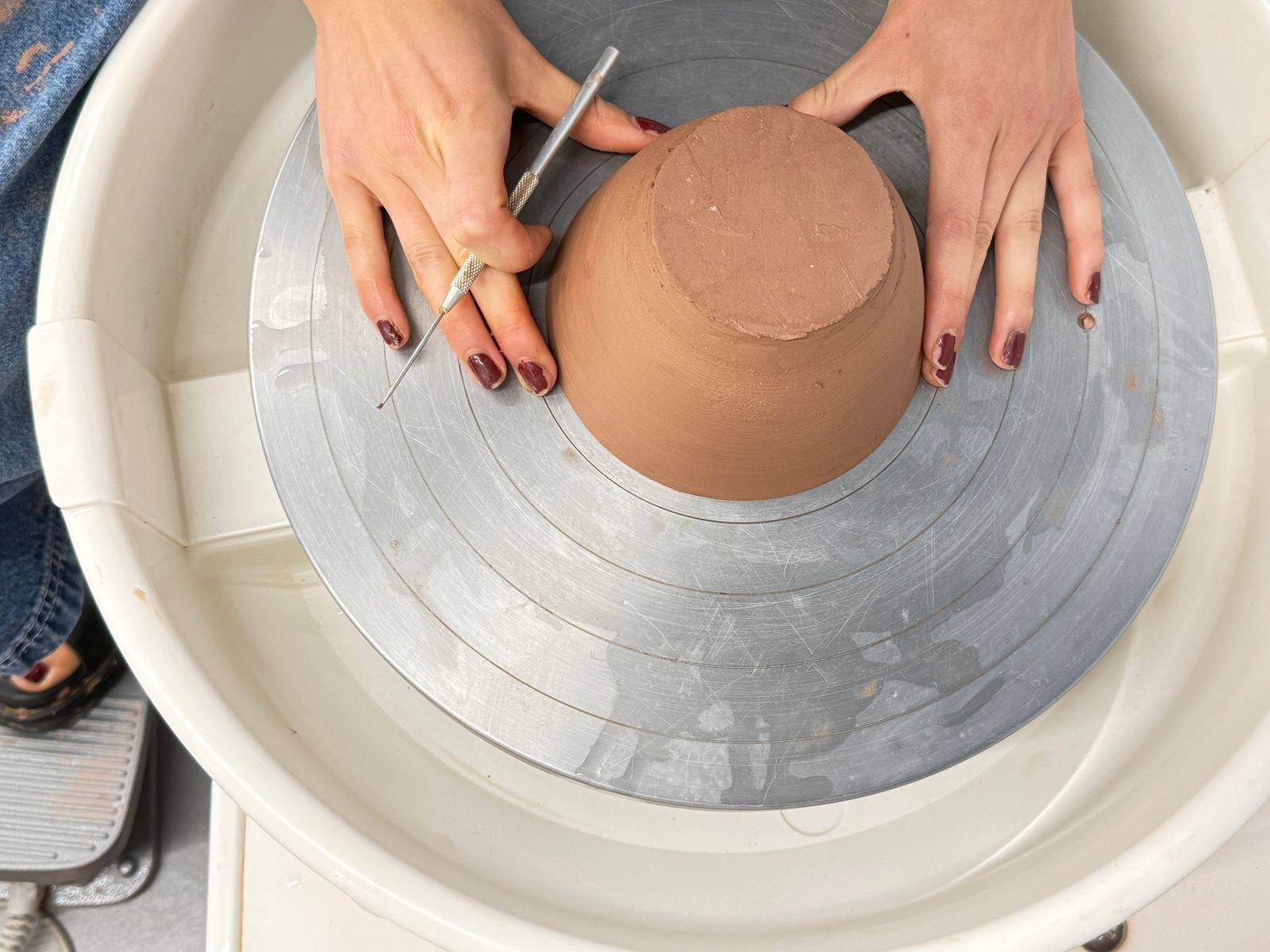 Top-down view of hands shaping clay on a pottery wheel
